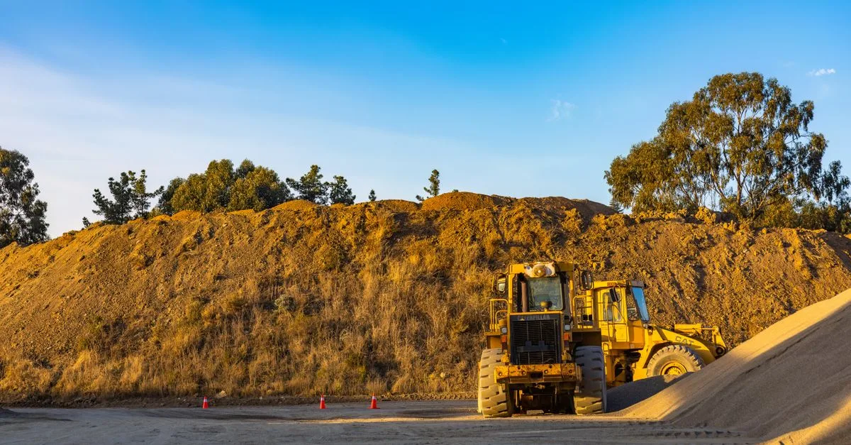 Aufgeschüttete Erdmiete auf einer Baustelle, davor ein Radlader